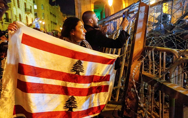 A demonstrator holds the Lebanese flag during a protest against a ruling elite accused of steering Lebanon towards economic crisis in Beirut, Lebanon January 19, 2020.