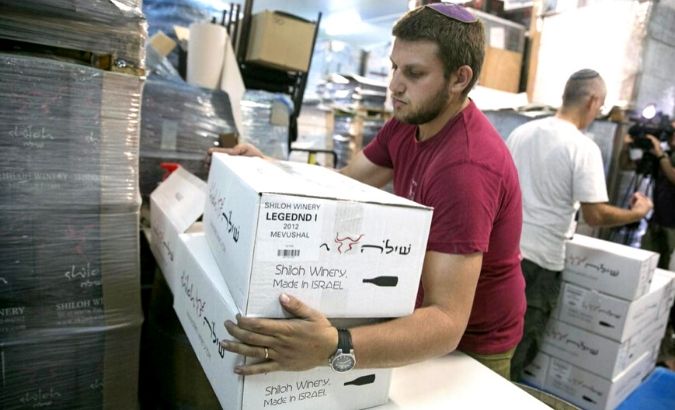 A worker carries boxes containing wine bottles for export at Shiloh Wineries, north of the West Bank city of Ramallah Nov. 8, 2015.