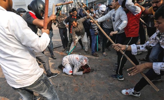 People supporting the new citizenship law beat a Muslim man during a clash with those opposing the law in New Delhi, Feb. 24, 2020.