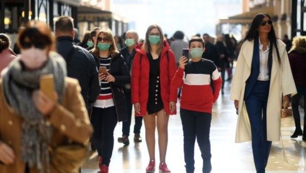 People wear masks as they walk in Milan, Italy, on Feb. 24, 2020.