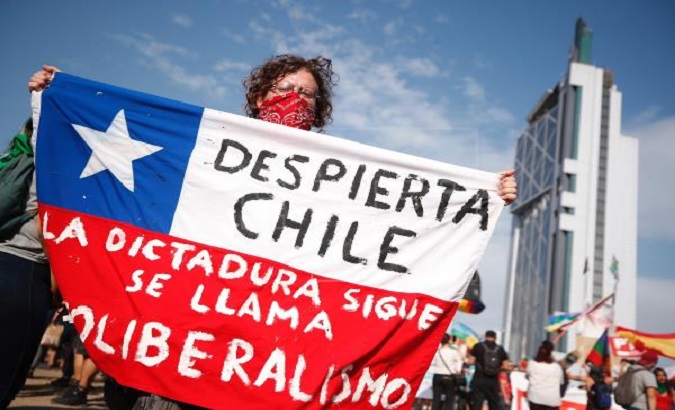 A demonstrator holds a flag during anti-government protests in Dignity Square, Santiago, Chile, Dec. 2019.