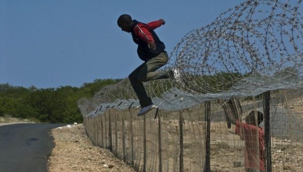 A 'border' jumper going over a fence separating Zimbabwe and South Africa. 