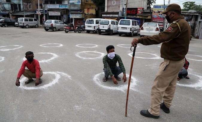 Police officers force people to crouch inside a circle to maintain a minimum social distance in Jammu, India, March 25, 2020.