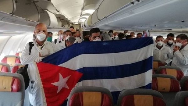 Cuban health workers hold a flag of their country inside an airplane bound for Italy, March, 2020.