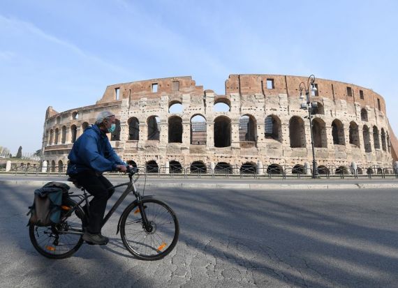 A man wearing a face mask rides a bike in Rome, Italy, March 22, 2020.