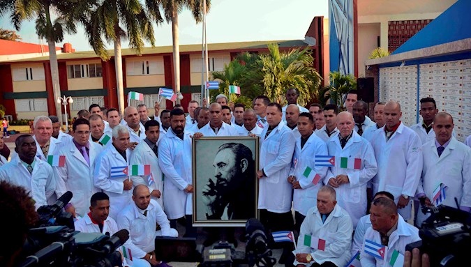 Members of the Henry Reeve medical brigade, which will provide support to Italy in the face of the crisis generated by COVID-19, pose with a photo of former Cuban President Fidel Castro