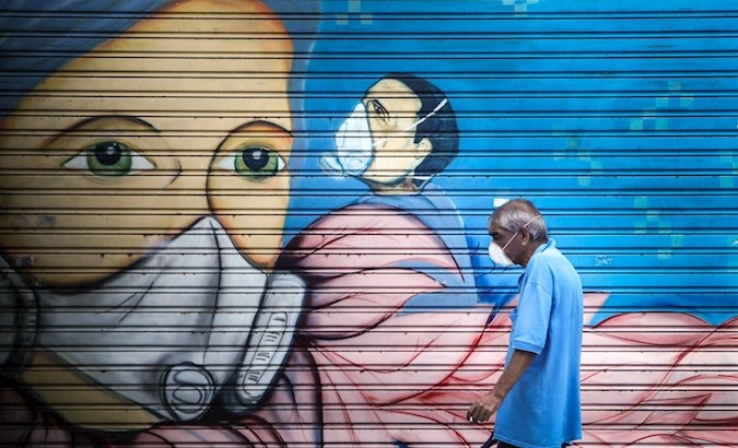 A man passes in front of a graffiti, Buenos Aires, Argentina, April 1, 2020.