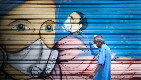 A man passes in front of a graffiti, Buenos Aires, Argentina, April 1, 2020.