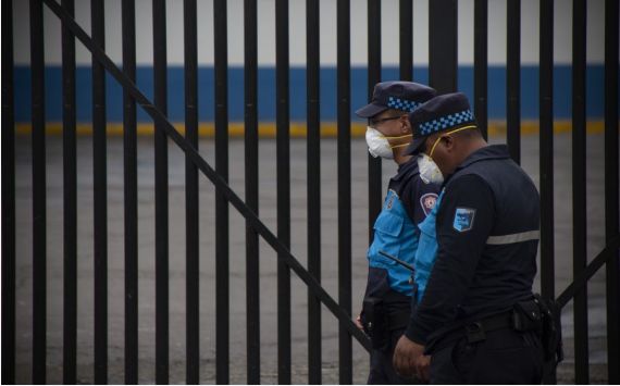 Security personnel wearing face masks walk past a hospital in Quito, Ecuador, March 17, 2020.