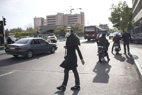 A woman wearing face mask crosses a street in Tehran, Iran, April 13, 2020.