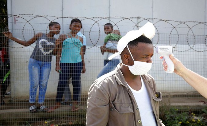 A health worker checks a mans temperature in Jika Joe informal settlement in Pietermaritzburg, South Africa, April 16, 2020
