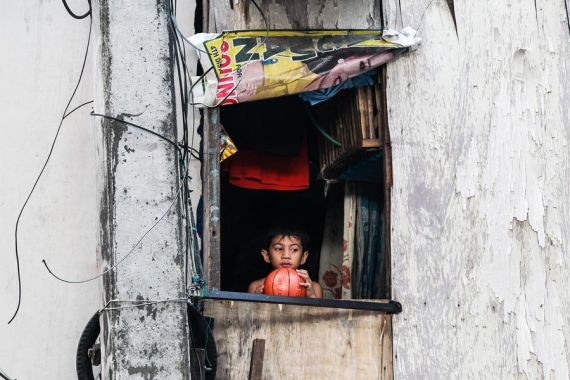 A boy holds a ball as he looks out of the window of his shanty at a slum area in Quezon City, the Philippines on April 23, 2020.