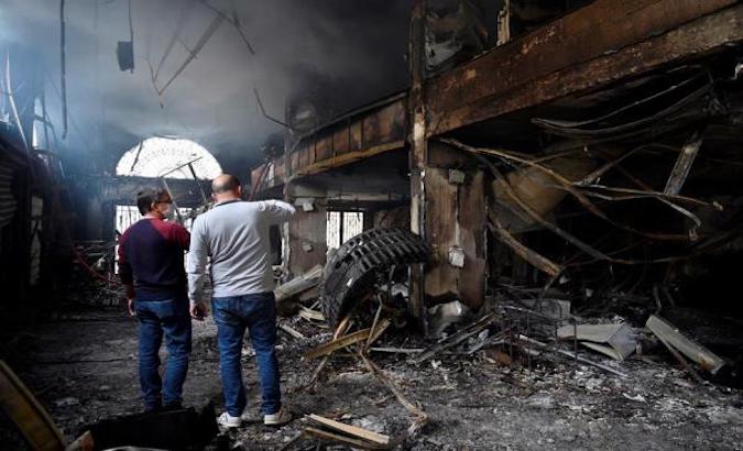 Lebanese men inspect a damaged bank that was set ablaze by protesters in Tripoli, northern Lebanon, April 29, 2020.