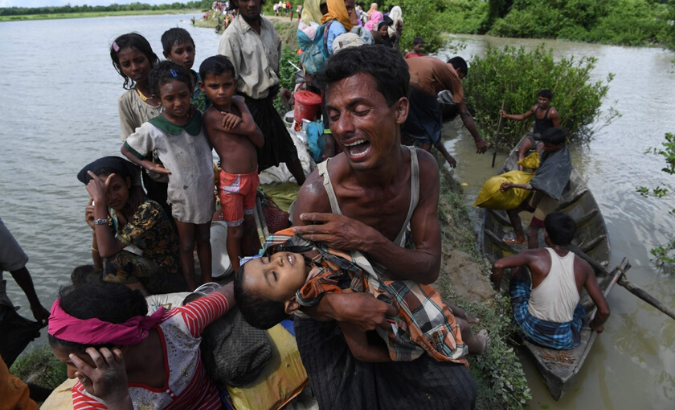 A Rohingya refugee reacts while holding his dead son after crossing the Naf river from Myanmar into Bangladesh in Whaikhyang on Oct. 9, 2017.