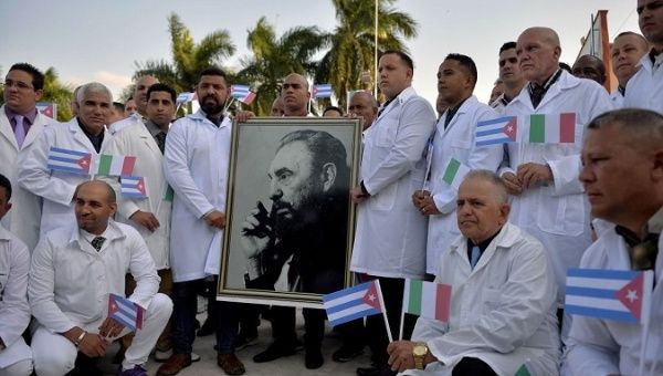 Members of the Henry Reeve Brigade pose with a photo of Fidel Castro, Havana, Cuba, 2020.