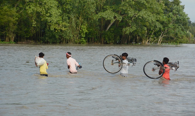 Indian villagers carry bicycles as they wade through flood water in the flood affected area of Goalbil, Baksa district, Assam, India July 30, 2020.