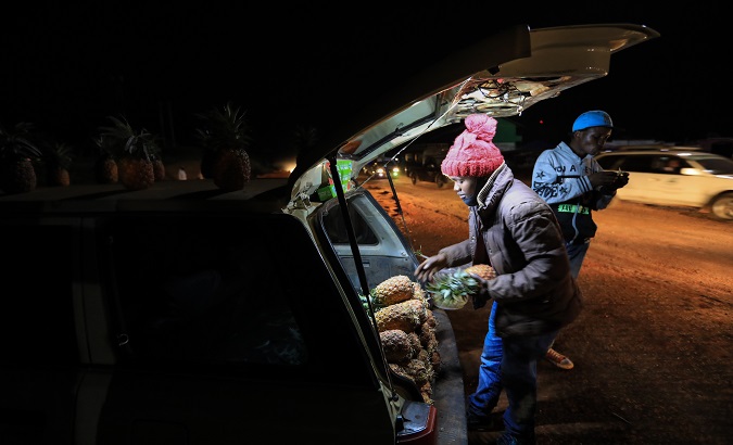 A Kenyan small-scale fruit vendor (C), sells pinnaples from the trunk of his car as he waits for customers a long a highway before the dusk to dawn curfew in the rural town of Denderu in Kiambu, Kenya. August 18 2020.