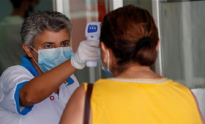 A health worker takes the temperature of a woman at a hospital in Mostoles, Madrid, August 26, 2020.