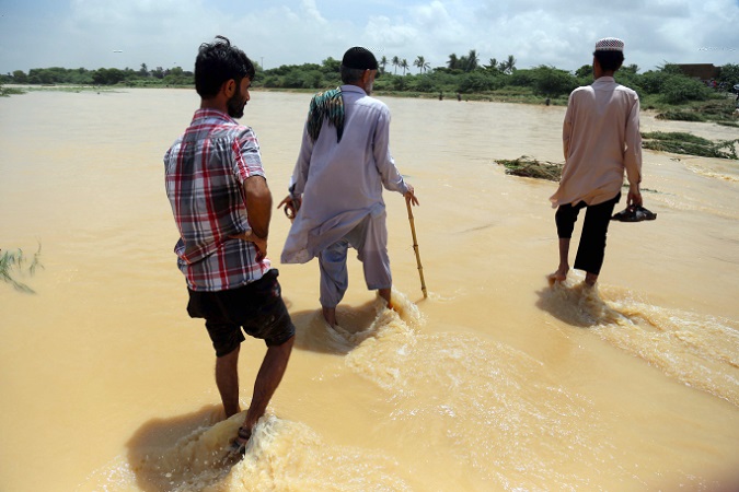 People walk at an inundated area after flooding water from Malir river due to heavy monsoon rains in Karachi, Pakistan, 26 August 2020.