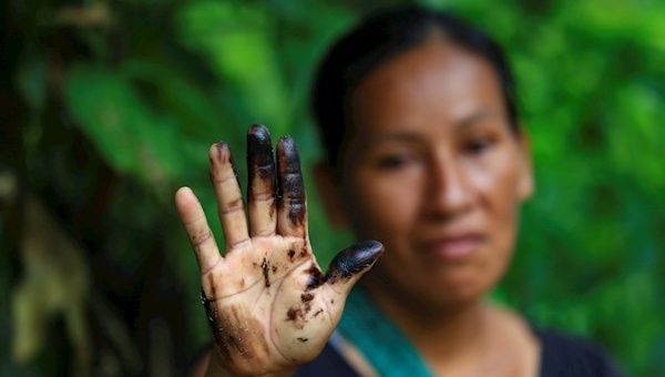 An Indigenous woman shows oil residues on her hand in Orellana province, Ecuador, Aug. 31, 2020.
