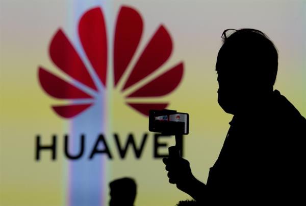 Silhouette of visitor next to the Huawei logo displayed on a screen at the Huawei stand at the International Consumer Electronics Fair (IFA) in Berlin, Germany. September 03, 2020.