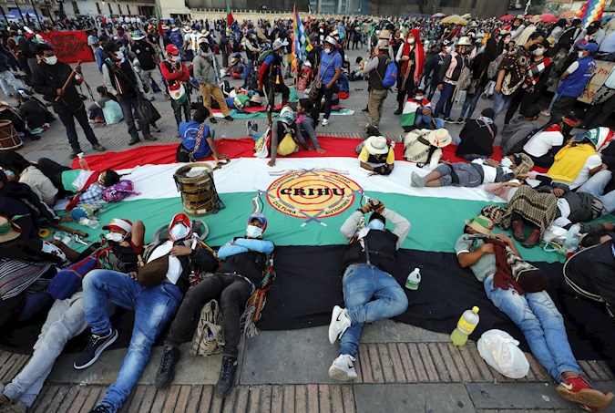 Several people rest on a flag of the Regional Indigenous Council of Huila (CRIHU) during the first day of minga demonstrations in Bolivar Square in Bogotá, Colombia. October 19, 2020.