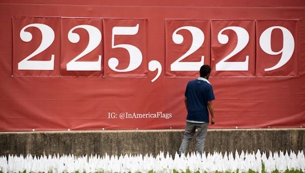 A man pauses in front of a sign showing a number representing a the US COVID-19 death toll, at a memorial for people who died with COVID-19. Washington, DC, USA. October 27, 2020.