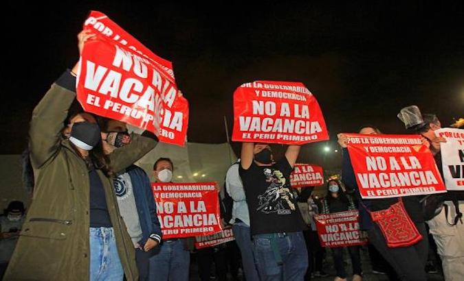Protesters hold signs against the vacancy of Martin Vizcarra, Lima, Peru, Nov. 9, 2020