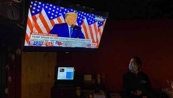 A restaurant worker wearing a protective face mask watches US President Donald Trump's speech on a TV during US presidential elections, at a restaurant in Beijing, China, 04 November 2020. 