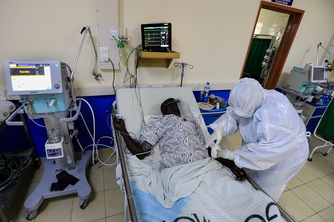 A Kenyan medical staff wearing Personal Protective Equipment (PPE) gear administers medication to a patient on an oxygen machine inside an Intensive Care Unit for COVID-19 patients at a hospital in Machakos, Kenya, 02 December 2020.