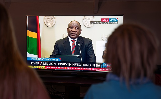 South Africans watch a live television broadcast of President Cyril Ramaphosa announcing new restrictions in an attempt to slow the COVID-19 surge across the country in Cape Town, South Africa, 28 December, 2020.