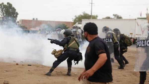 Police officer throws tear gas canisters at demonstrators, Viru, Peru, Dec. 30, 2020.