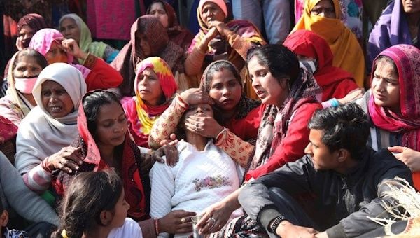 Relatives of one of the victims stand next to her body as they block the Delhi-Meerut highway, India, January 4, 2021.