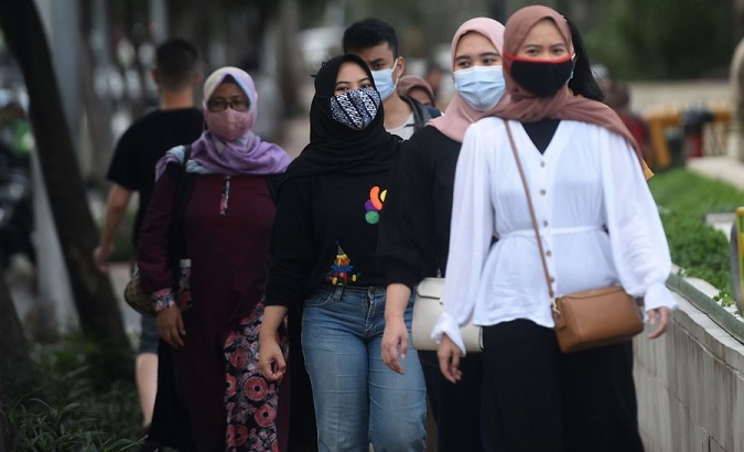 People wearing face masks walk on a main street in Jakarta, Indonesia, Dec. 11, 2020.