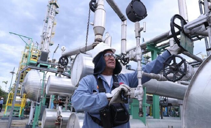 A worker operates valves in a refinery, Peru.