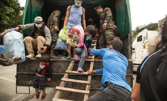 A group of migrants descend from a truck on the Guatemala-Mexico border, Jan. 19, 2021.