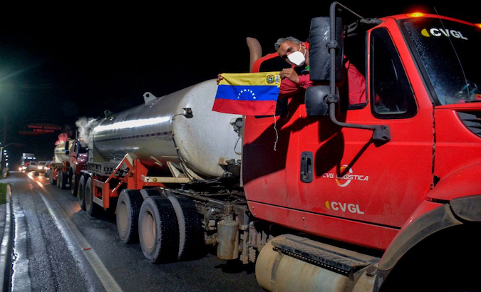 A man holds a Venezuelan flag from a truck loaded with oxygen heading to Manaus, Brazil, Jan. 18, 2021.