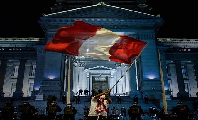 A protester waves the flag in front of the Congress, Lima, Peru, Nov. 15, 2020.