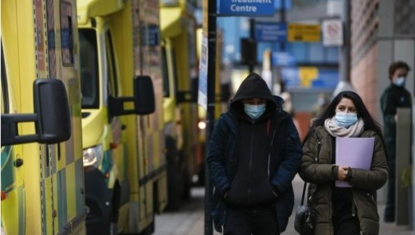 People wearing face masks walk past ambulances at The Royal London Hospital in London, Britain, on Jan. 26, 2021.