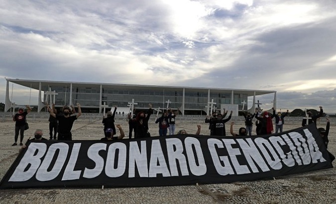Citizens show a poster calling Bolsonaro genocidal in Brasilia, Brazil, March 19, 2021. 