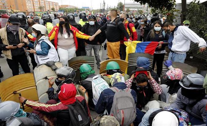 Protesters shield themselves from police officers in Bogota, Colombia, May 2021.