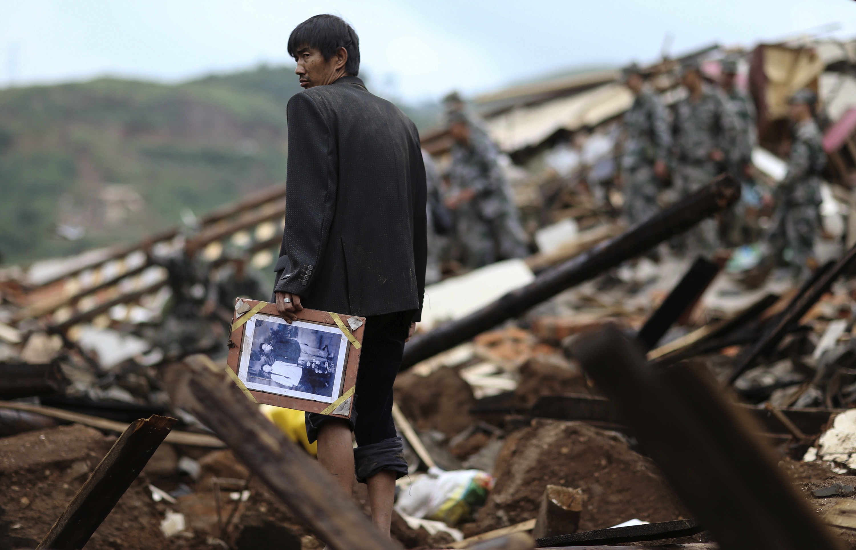 A man holds a picture as he stands among debris of collapsed buildings (Photo:Reuters)