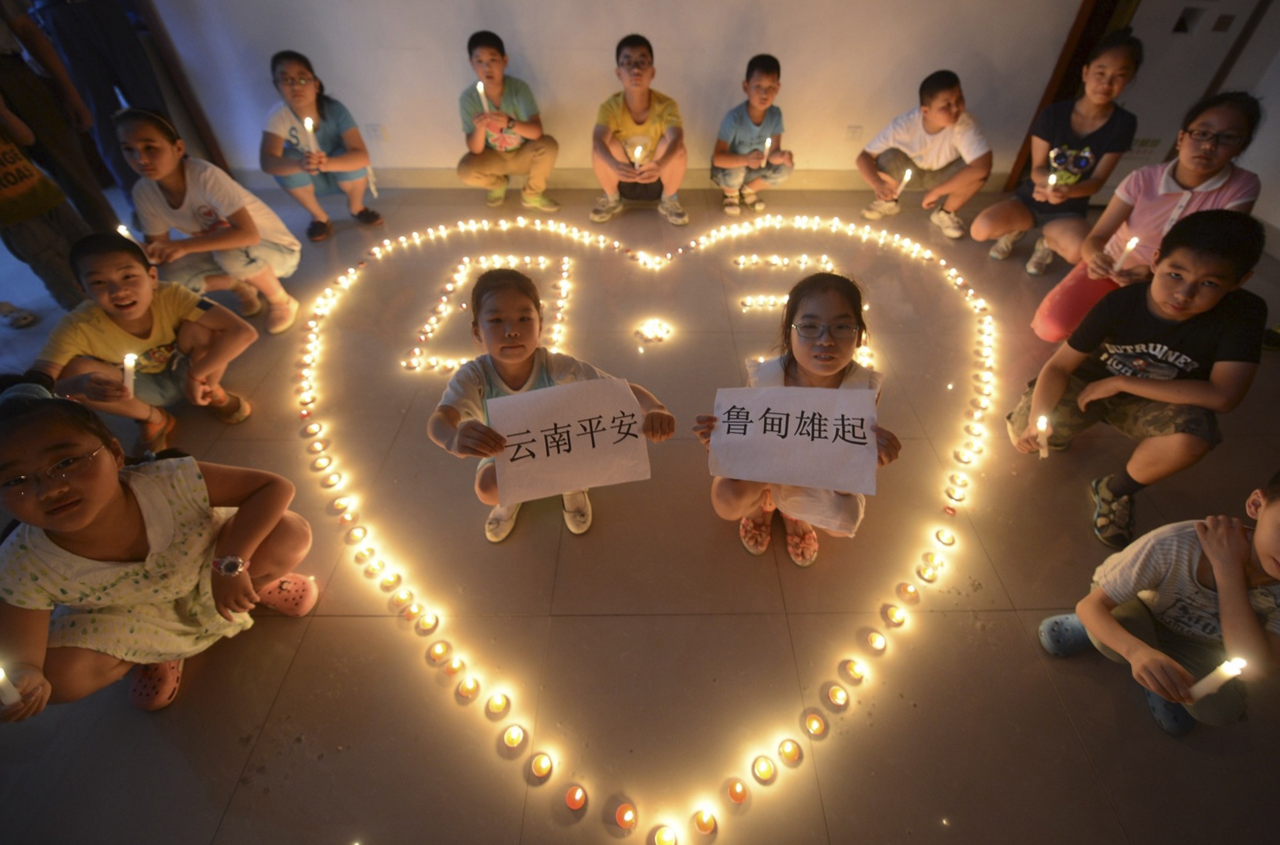 Children hold candles and signs, as they pose for a picture during a event organised to pray for those affected by a magnitude 6.3 earthquake that hit Longtoushan town, Ludian county, in Yangzhou. (Photo: Reuters)