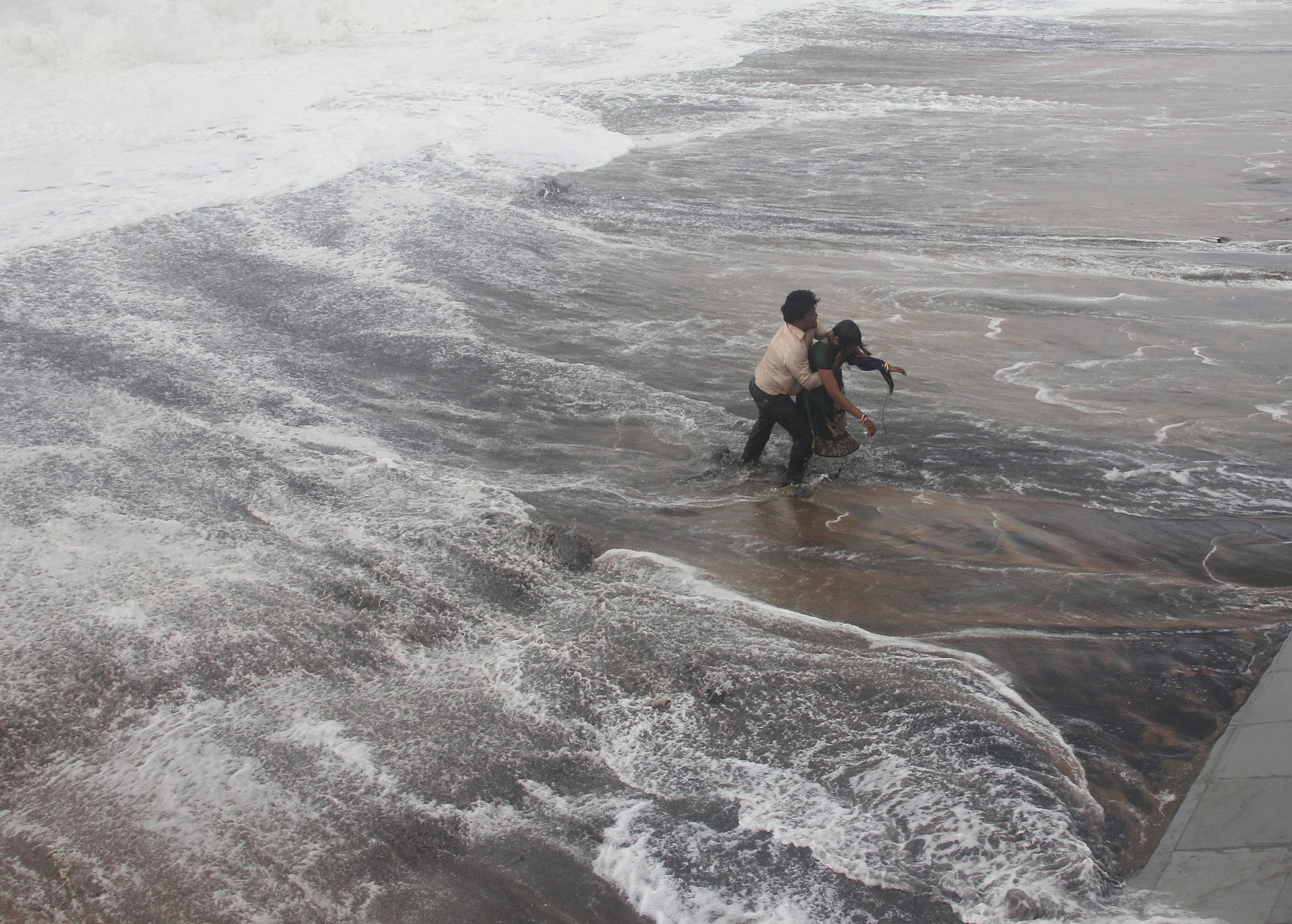 A man carries his wife to a safer ground after a wave hits a beach in Gopalpur in Ganjam district in the eastern Indian state of Odisha October 12, 2014. (Photo: Reuters)