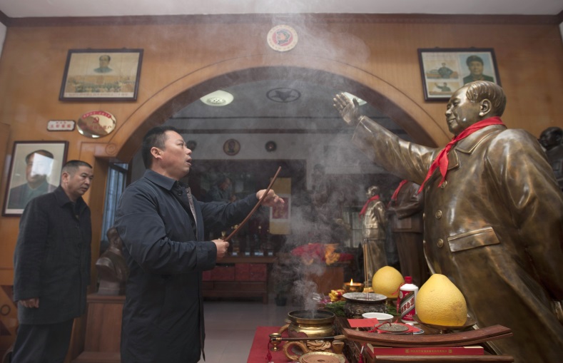 Tian Haiming, a sculptor, burns incense in front of a copper statue of China's late Chairman Mao Zedong before handing it to the buyer, in Shaoshan, Hunan province, Dec. 8, 2014.