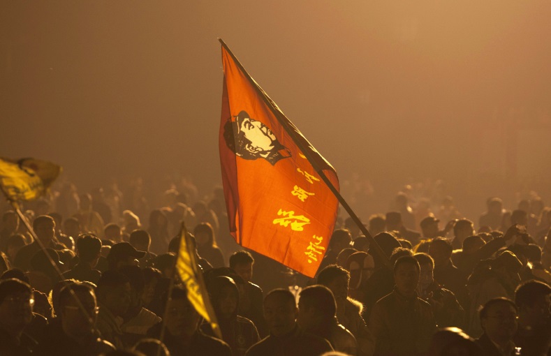 A person holds a flag of China's former Communist Party leader Mao Zedong, as people gather at a square to celebrate Mao's 121st birth anniversary in his hometown of Shaoshan, Hunan province, Dec. 25, 2014.