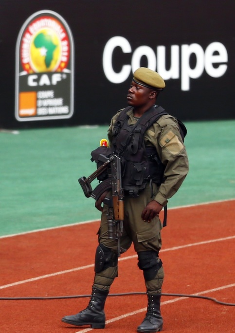 A soldier takes his position as Equatorial Guinea's players check the field of the Estadio de Bata 