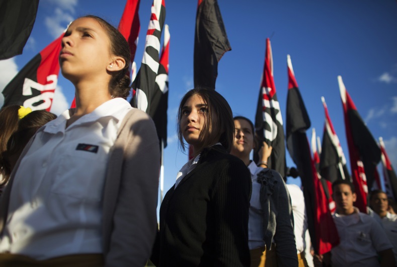 Student Karla Cantillo (C), 13, holds a flag underneath the memorial of Jose Marti on Revolution Square in Havana on January 28, 2015