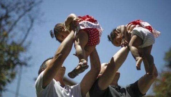 A gay couple holds their one-year-old twin daughters at a playground in West Hollywood, California.