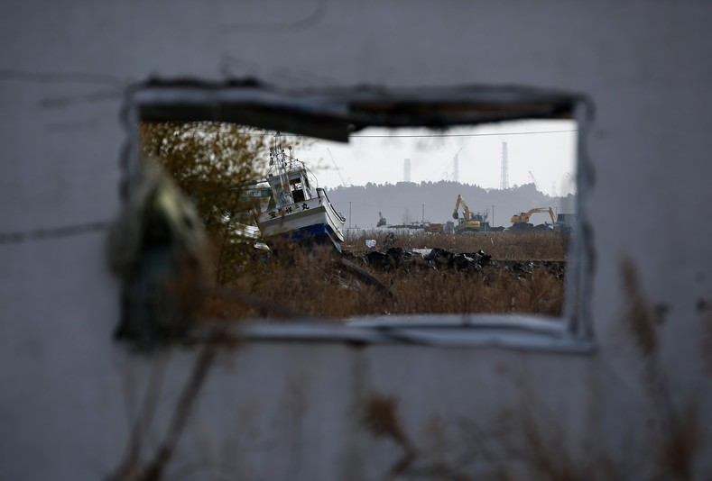 A fishing boat washed up by the March 11, 2011 tsunami and black plastic bags containing radiated soil from the decontamination operation are seen in front of cranes and chimneys of Tokyo Electric Power Co's (TEPCO) Fukushima Daiichi nuclear power plant through an abandoned house prefecture Feb. 24, 2015. 